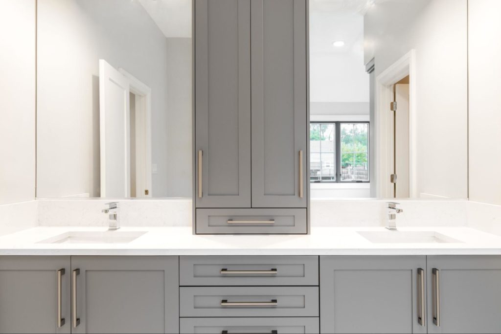 Bathroom with grey semi-custom cabinets with gold hardware.