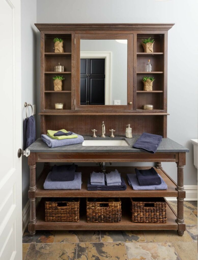 Rustic wooden bathroom cabinet with open shelving, wicker baskets for storage, and a built-in mirror, enhancing the traditional decor.