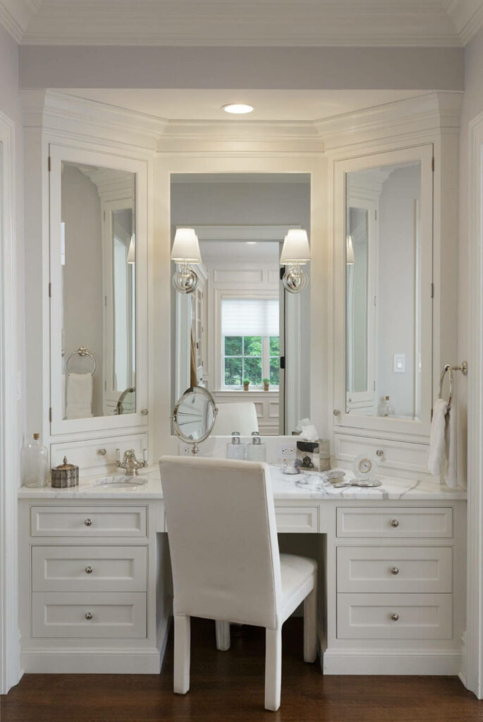 Bright bathroom vanity area with white cabinetry providing generous storage, complete with a seated makeup area.