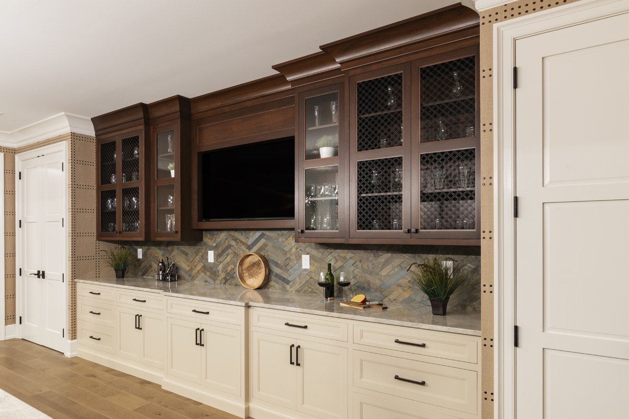 Custom cabinets with a dark wood finish, diamond-patterned glass doors, juxtaposed against a geometric tile backsplash and a sleek countertop.
