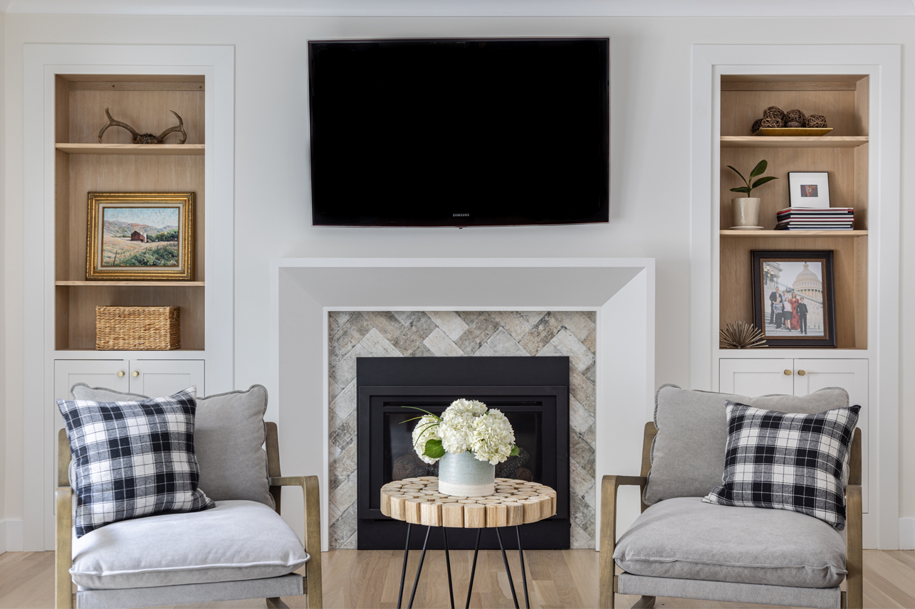 Cozy living room featuring custom cabinets with wooden shelves flanking a modern television and fireplace, adorned with art pieces, books, and decorative items.