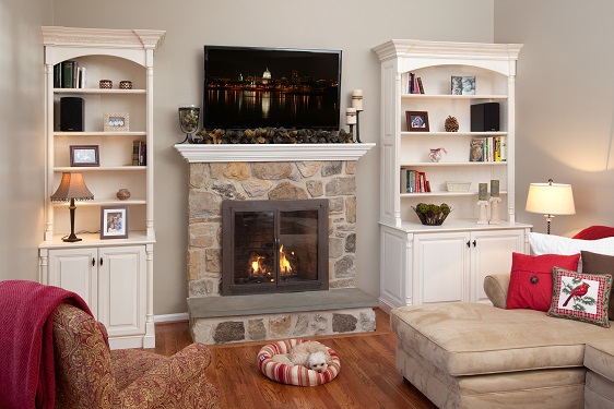 Custom white bookshelves framing a stone fireplace in a warm and inviting living room, complete with a plush sofa and soft, comforting lighting.