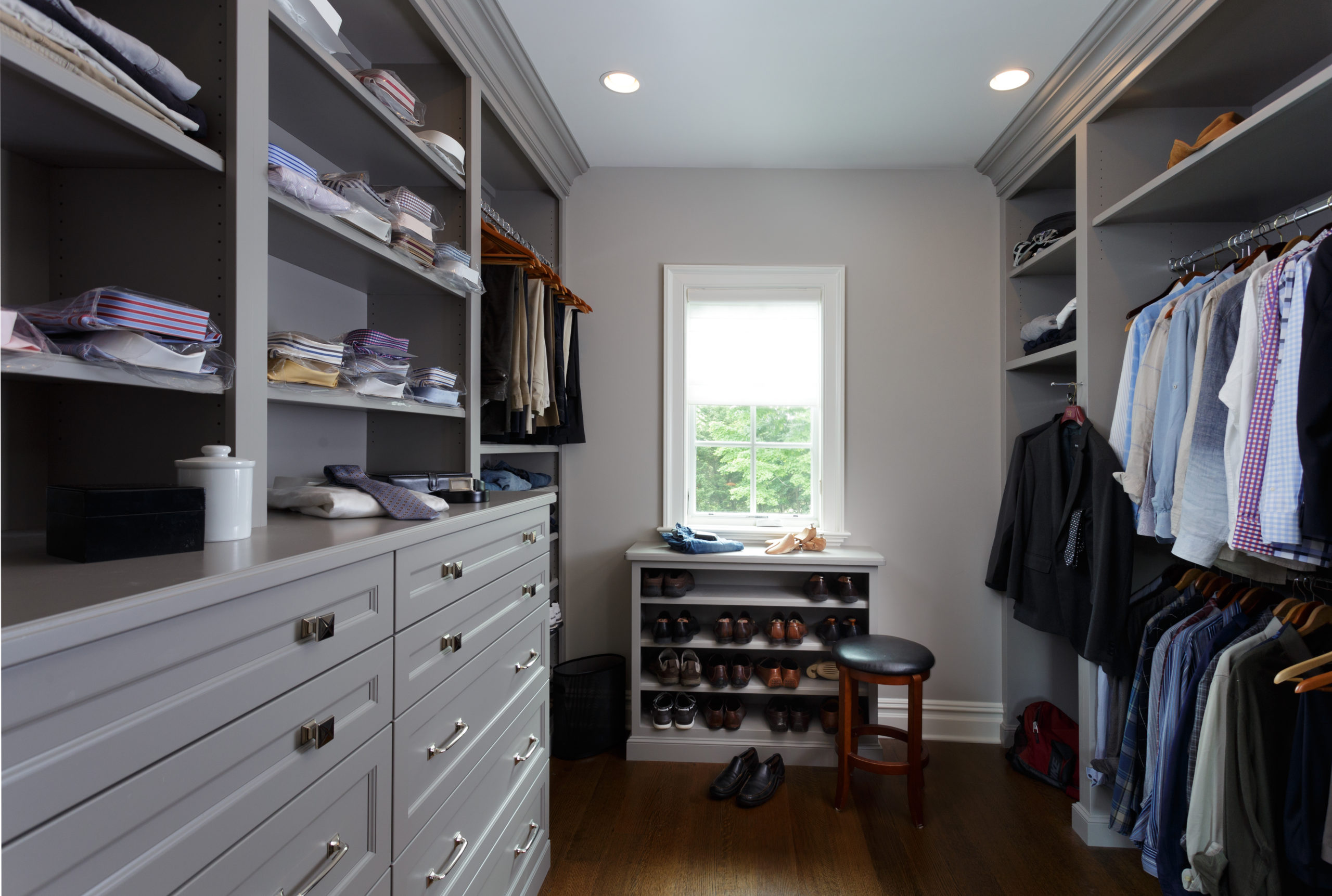 A meticulously organized walk-in closet with custom cabinetry featuring numerous drawers and shelves.