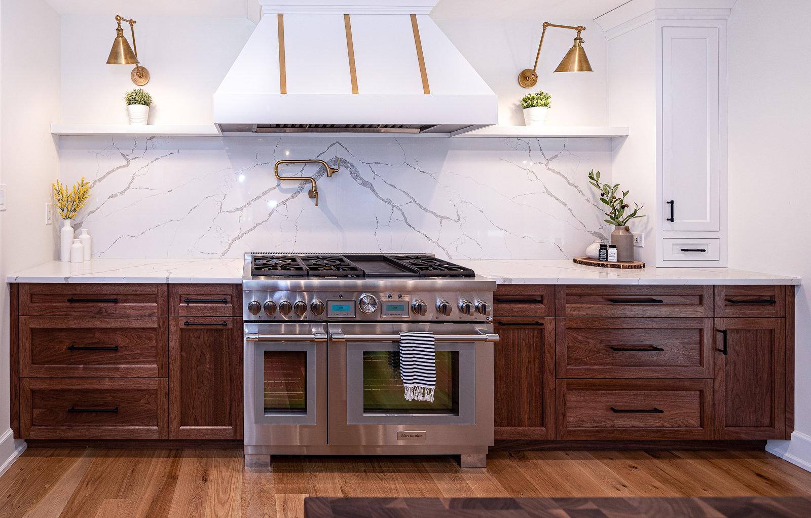 A gourmet kitchen adorned with exquisite walnut custom cabinets featuring contemporary hardware, a professional-grade range, and a marble backsplash, all within a refined custom cabinet gallery.