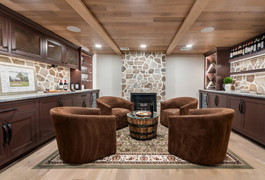 A luxurious home tasting room featuring dark wood luxury custom cabinetry, a stone fireplace, and a warm, inviting seating area.